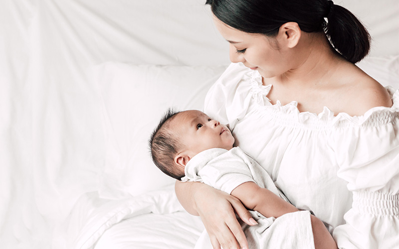 Mother holding infant baby, considering secondary infertility treatment.