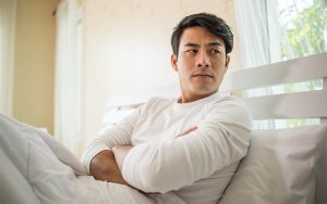 Person sitting in bed with arms crossed.
