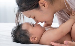 Mother smiling lovingly at her baby in bed.