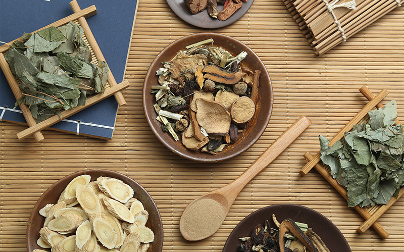 Assorted Chinese herbal medicine ingredients in small ceramic bowls.