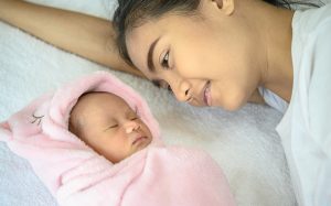 Mother smiling at her sleeping newborn