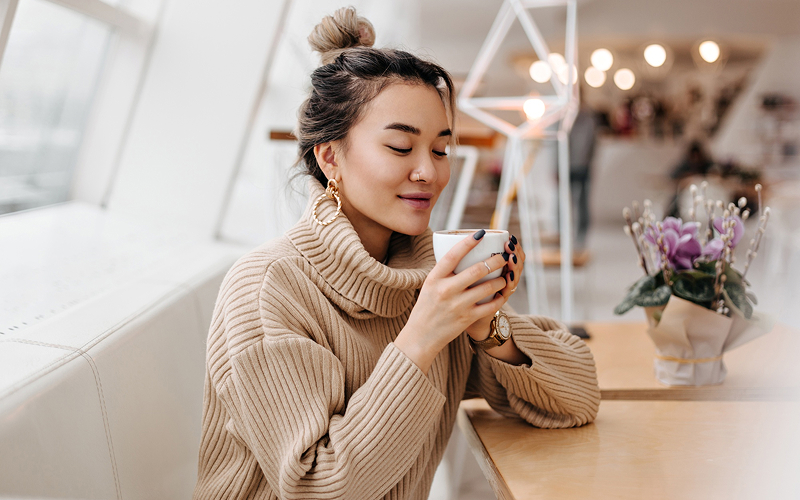 Woman drinking a warm beverage to support menstrual wellness.