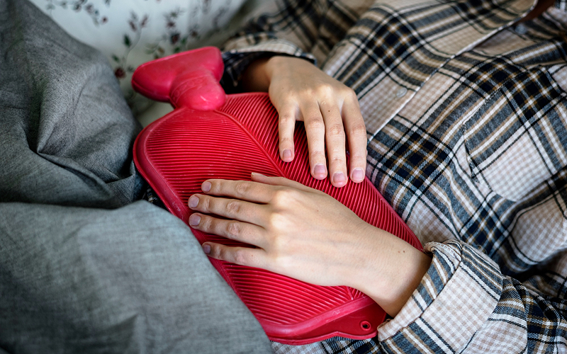 Woman using a hot compress for period discomfort.